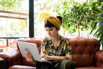Teen girl sitting on sofa and using laptop computer