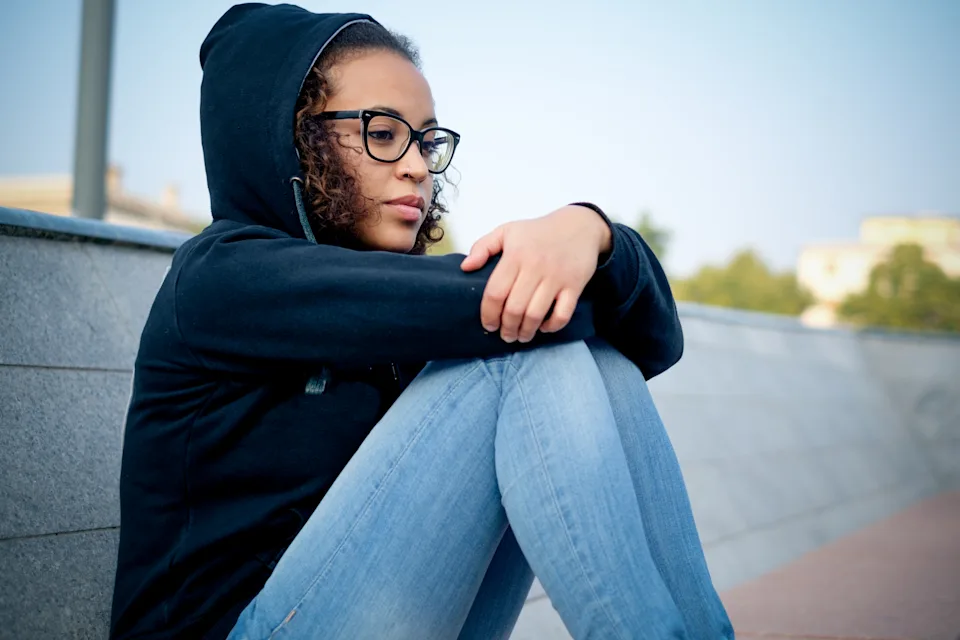 Teenage girl in glasses sitting on the ground