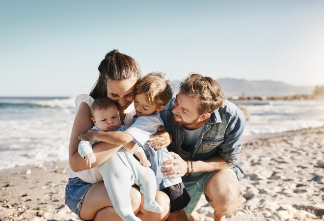 small family hugging at the beach