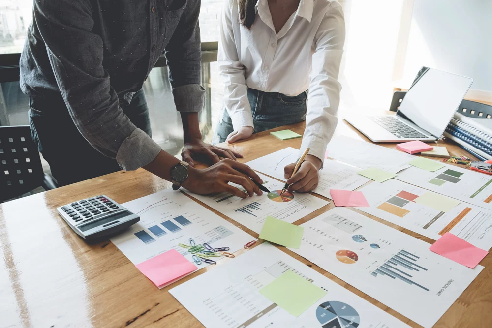 Two people working at a desk with various papers neatly organized