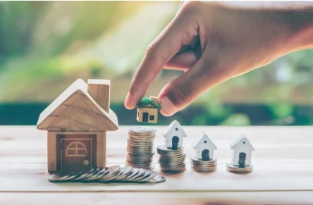 Tiny toy houses stacked on coins