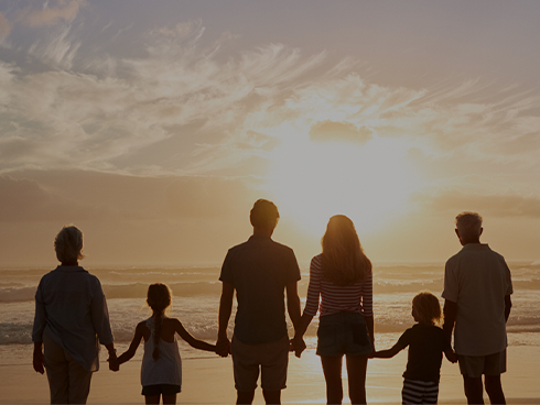 Family standing on beach at sunset holding hands