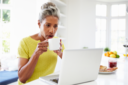 A woman drinking coffee and using a laptop