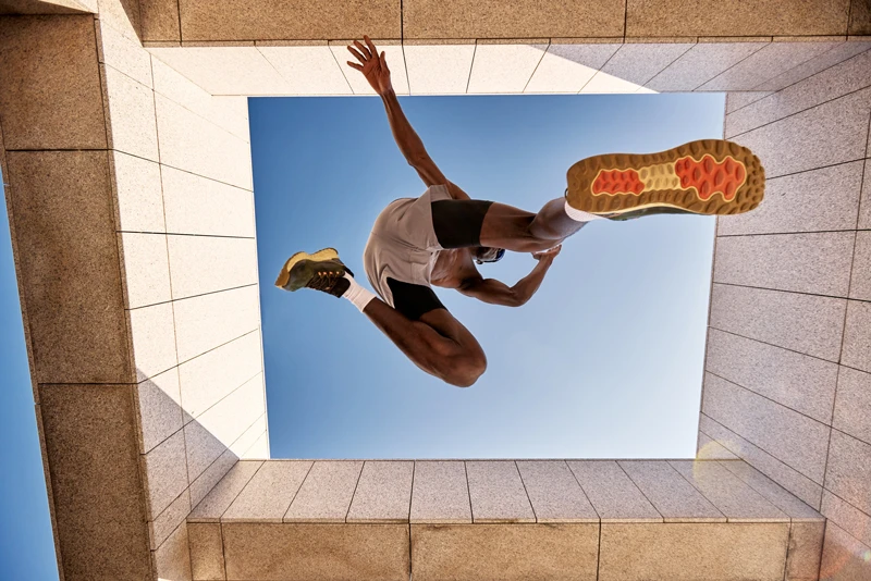 Athlete jumping through a modern architectural opening against a blue sky