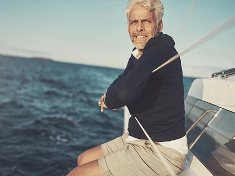 An older man sitting on the edge of a sailboat