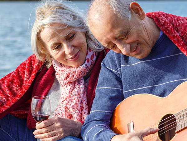 A senior couple enjoying a quality time together with wine and music by the water