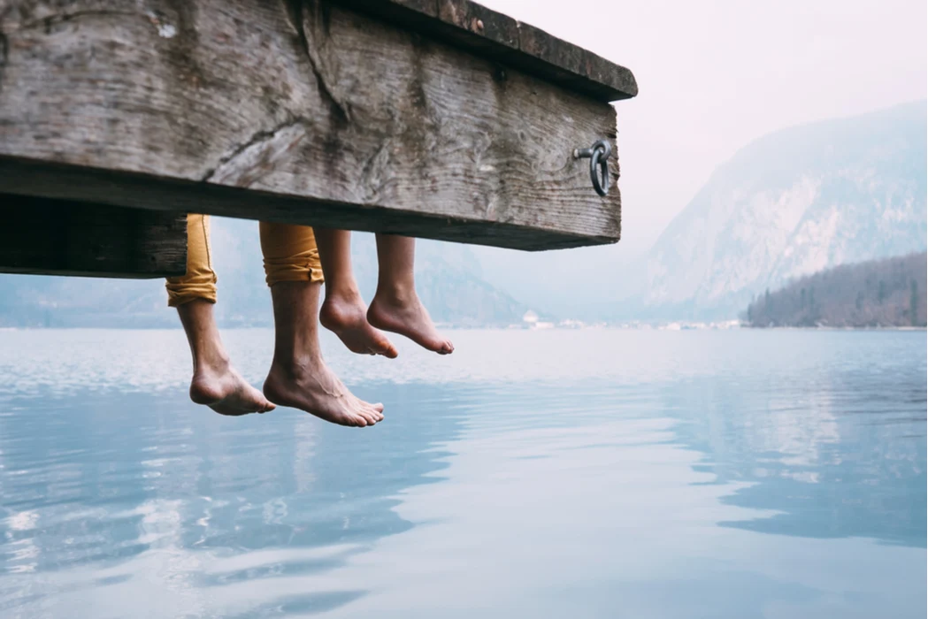 People sitting with their legs hanging off a pier