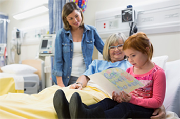 A woman sitting in a hospital bed with a young girl and another woman