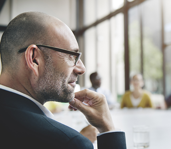 A man with glasses listening at the meeting