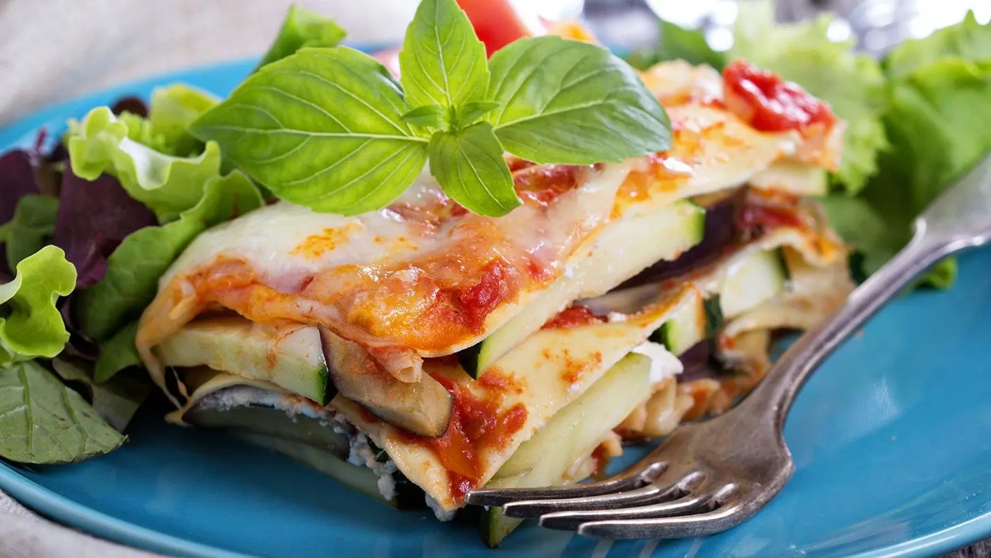 Delicious vegetable lasagna layered with fresh vegetables, ricotta cheese, and marinara sauce, baked to perfection and garnished with fresh basil.