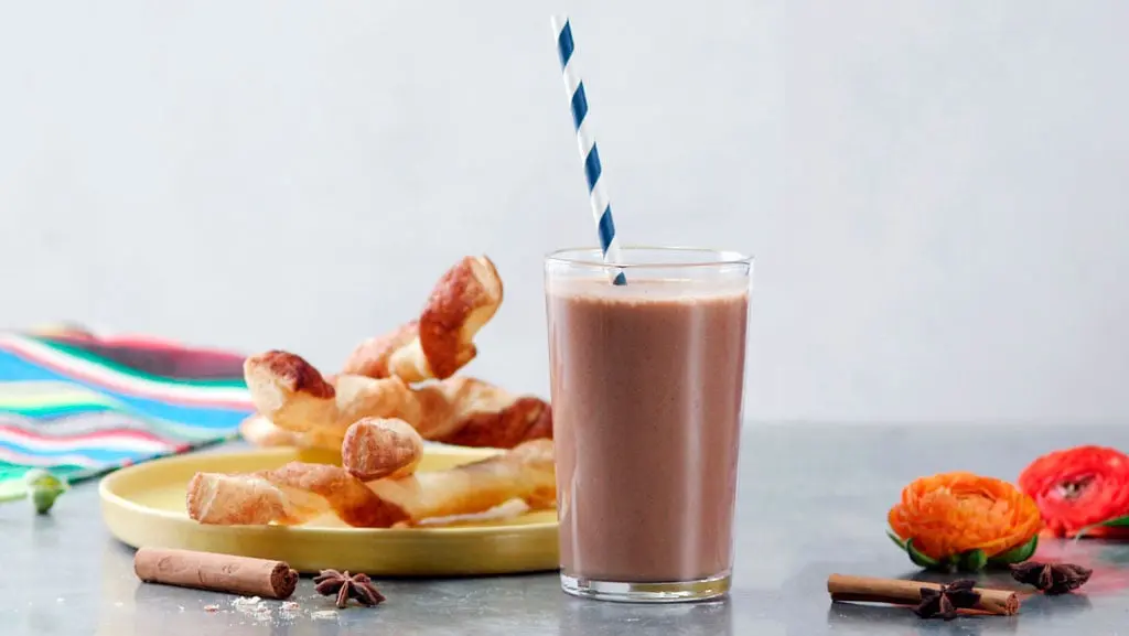 Frozen champurrado cinnamon twists, beautifully arranged and dusted with cinnamon sugar, served on a rustic plate, perfect for a sweet treat or dessert.