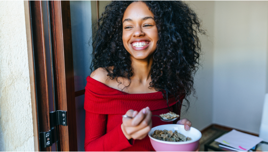 Woman smiling as she eats a bowl of cereal