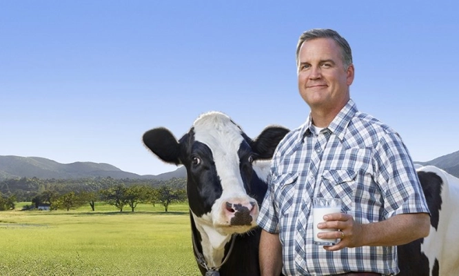 El agricultor Dave con una vaca y un vaso de leche marca Lactaid