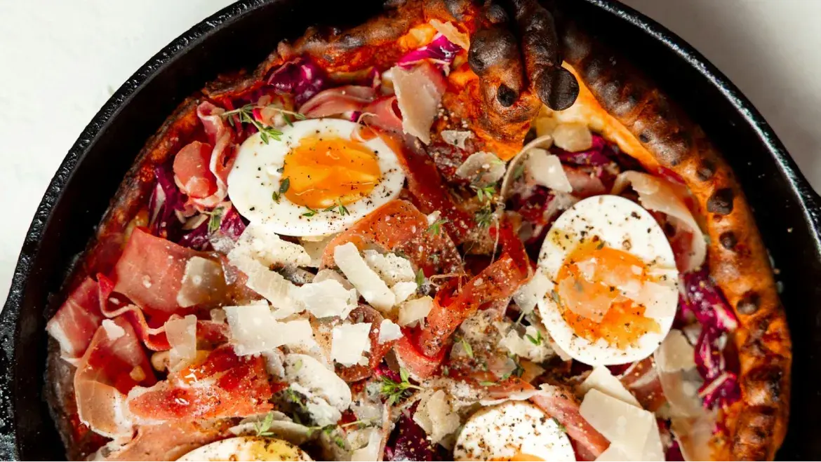 Delicious Savory Dutch Baby with eggs, ham, and herbs in a skillet