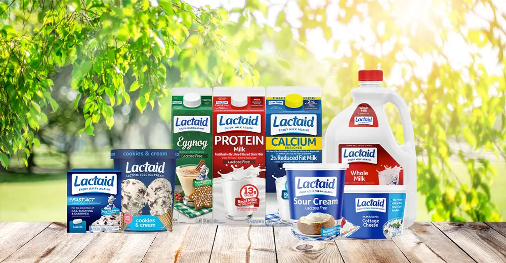 Array of Lactaid products on a wood table with a background of trees and sunshine.