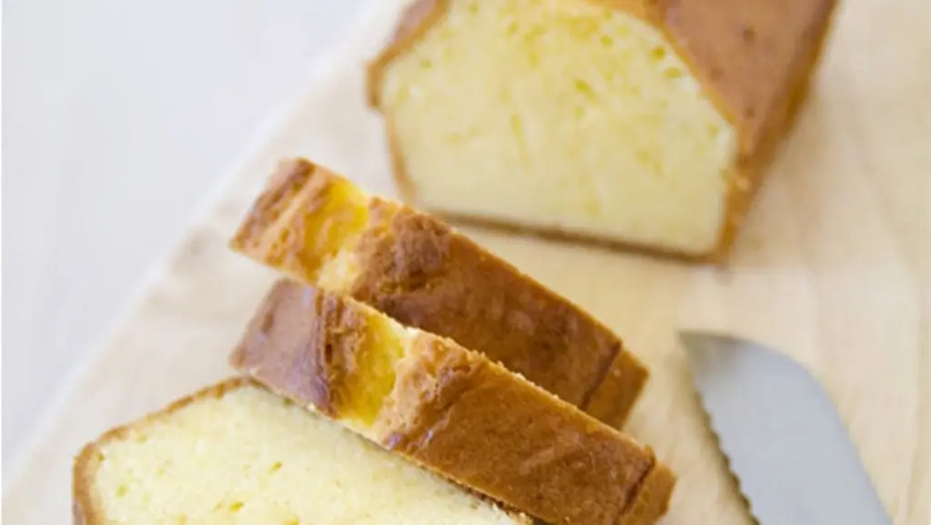 Freshly baked homemade pound cake sliced on a rustic wooden platter, showcasing a golden-brown crust and a soft, moist interior.