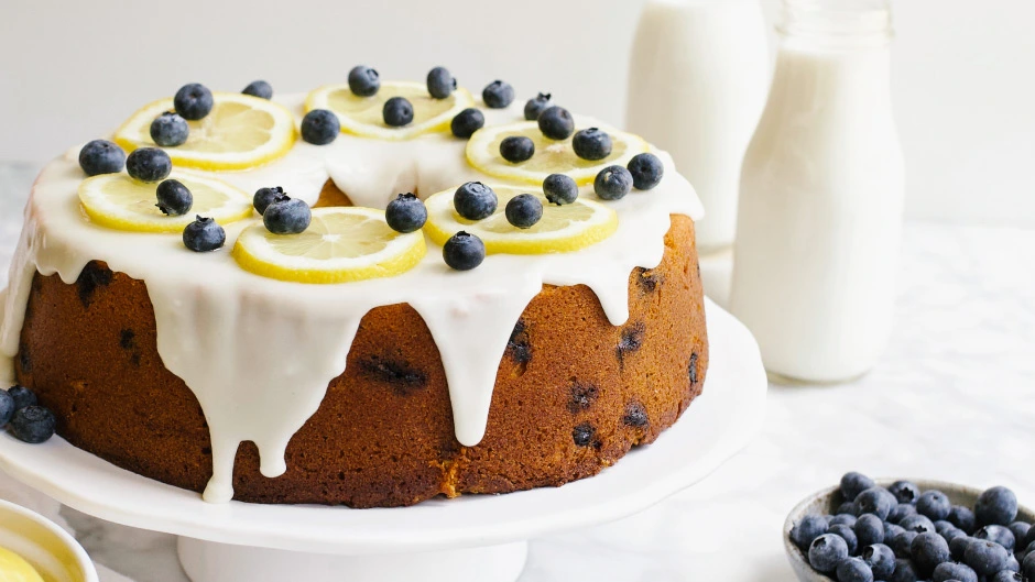 Lemon blueberry pound cake with icing and fresh lemon slices and blueberries on top.