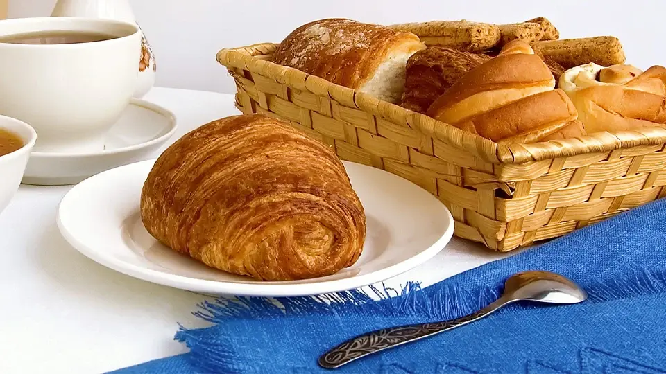 Fresh croissant served with tea and a bowl of fruit puree
