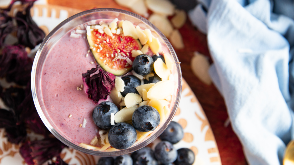 Vibrant hibiscus chia seed pudding served in a glass, topped with fresh berries and a sprinkle of coconut, offering a colorful and nutritious dessert option.