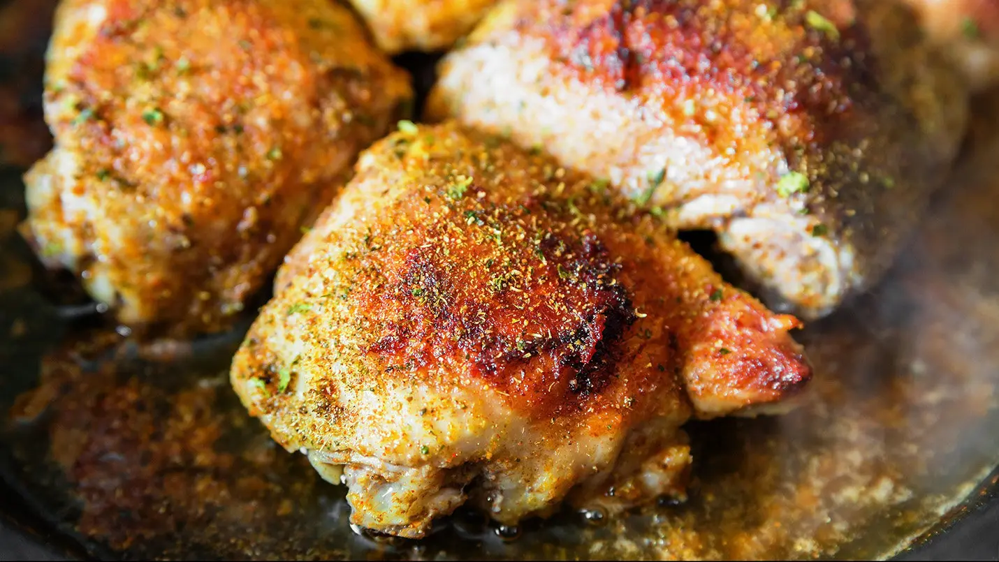 Savory curried chicken thighs garnished with fresh cilantro, served on a plate with vibrant vegetables and a side of rice, showcasing a flavorful and aromatic dish.