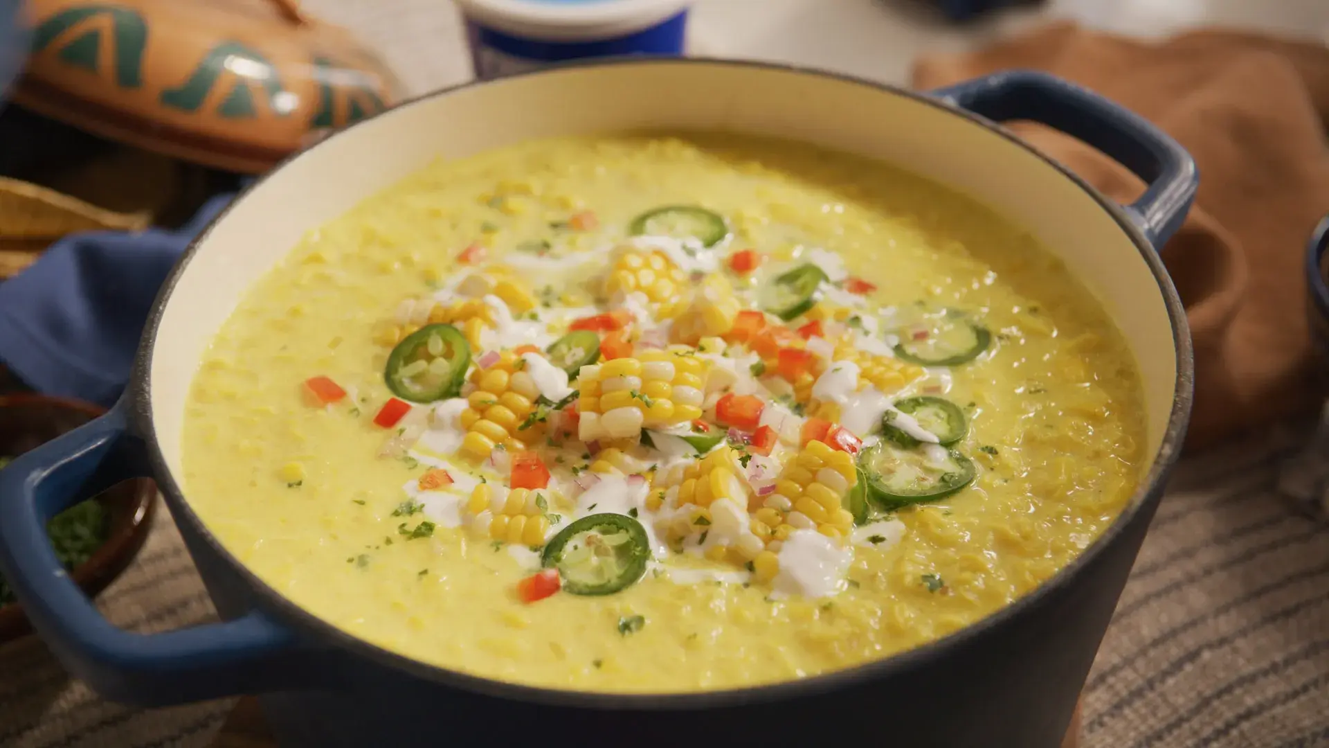 A vibrant bowl of creamy corn soup garnished with herbs, showcasing a delicious and inviting presentation on a rustic table.