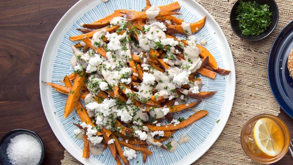 Loaded sweet potato fries with cheese and parsley with an iced tea