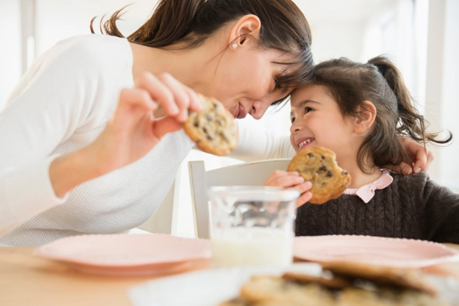 Woman and little girl eating cookies with milk
        