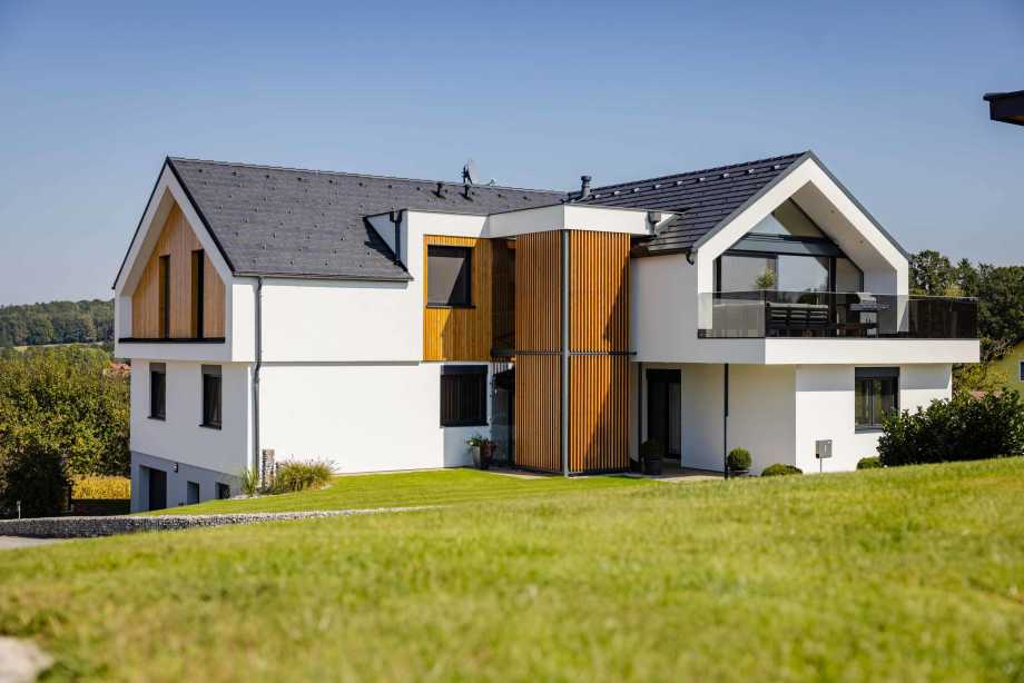 modernes Haus mit Balkon in sonniger Lage, Steildach mit grauen Dachziegeln und verschiedenen Dachzubehör sorgt für ein sicheres und angenehmes Wohnen