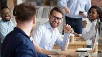 glückliche junge Männer und Frauen von BMI Österreich während einer Konversation im Büro