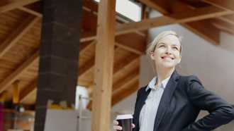 Frau mit Kaffee in der Hand blick zufrieden auf den Dachausbau 