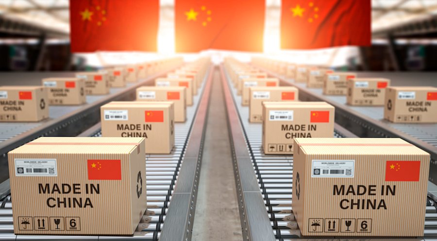Kartonnen dozen met "Made in China" op transportbanden in een magazijn, met Chinese vlaggen op de achtergrond. 