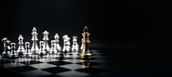 Gold king chess piece facing silver pieces on a chessboard against dark background, symbolizing strategy and competition.