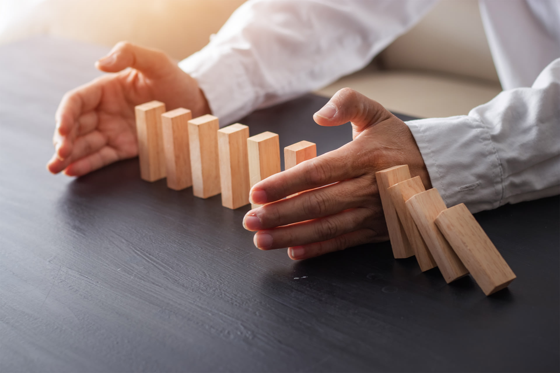 Een man die verschillende houten domino stukken beschermt