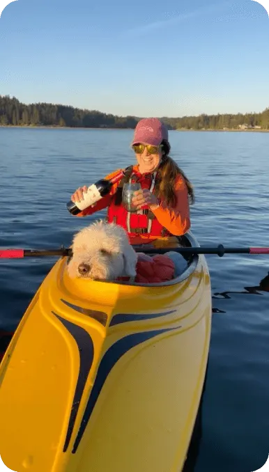 Woman kayaking with her dog pours a glass of wine