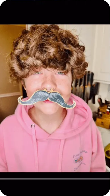 Creator poses in a wig and fake mustache in a still taken from TikTok
