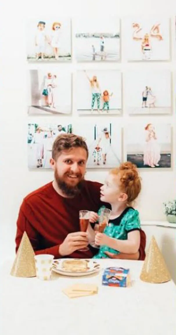 Father and daughter smiling in front of a wall of family photos with Kraft products