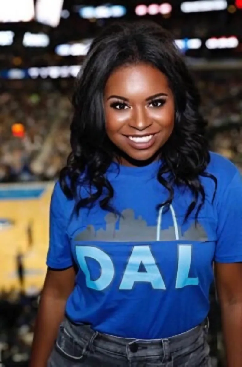 Woman looks into camera wearing a Dallas Mavericks shirt