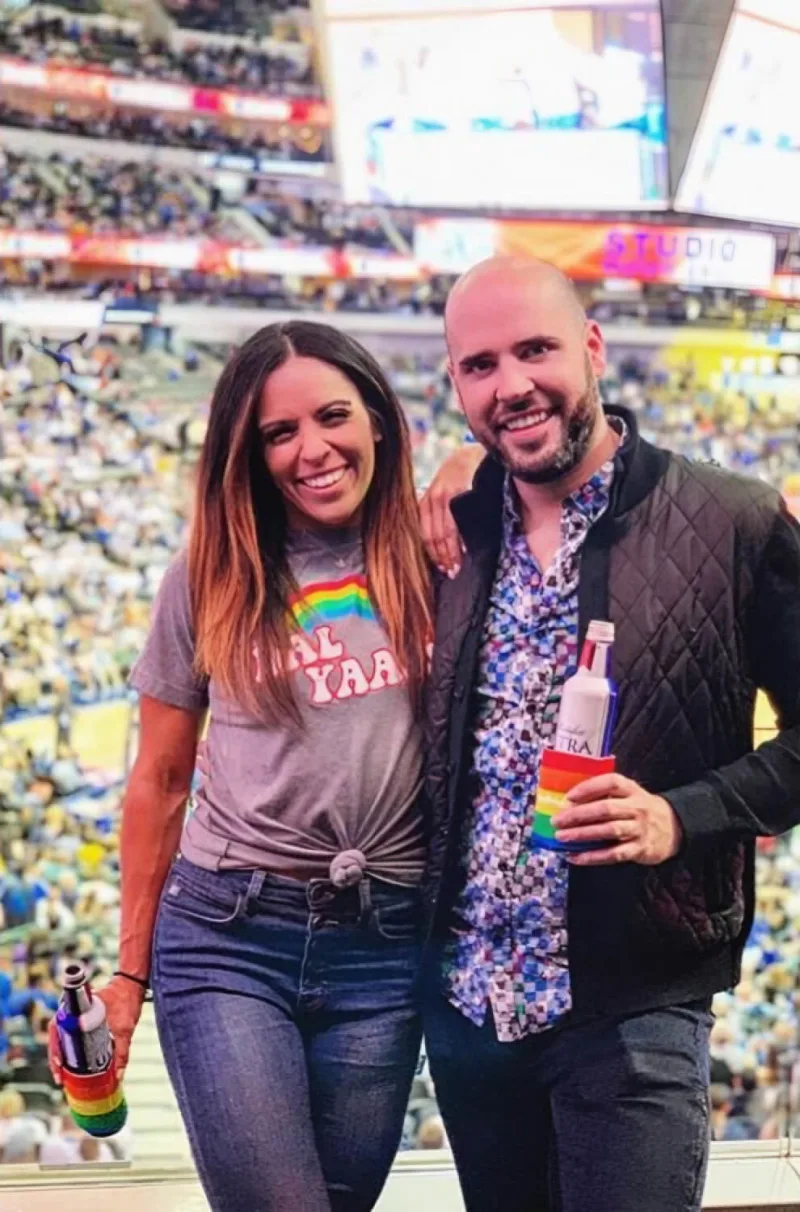 Couple poses with drinks with rainbow drink holder for Mavs Pride event