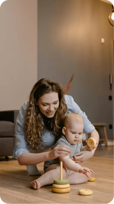 Woman playing ring game on floor with small baby