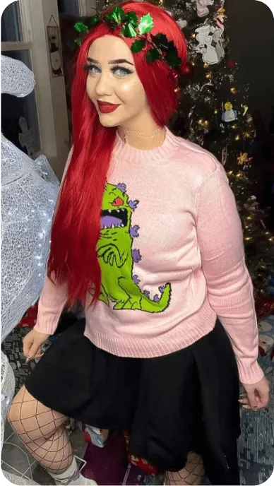 Red haired creator poses in dinosaur sweater from Hot Topic