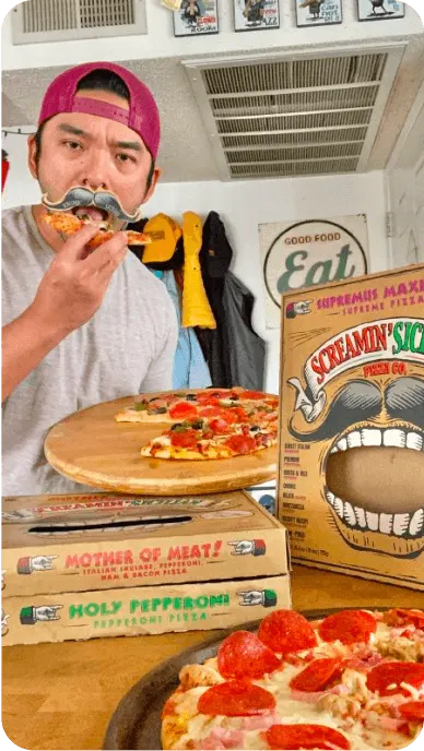 Creator with fake mustache eats pizza next to Palermos pizza boxes in an Instagram post