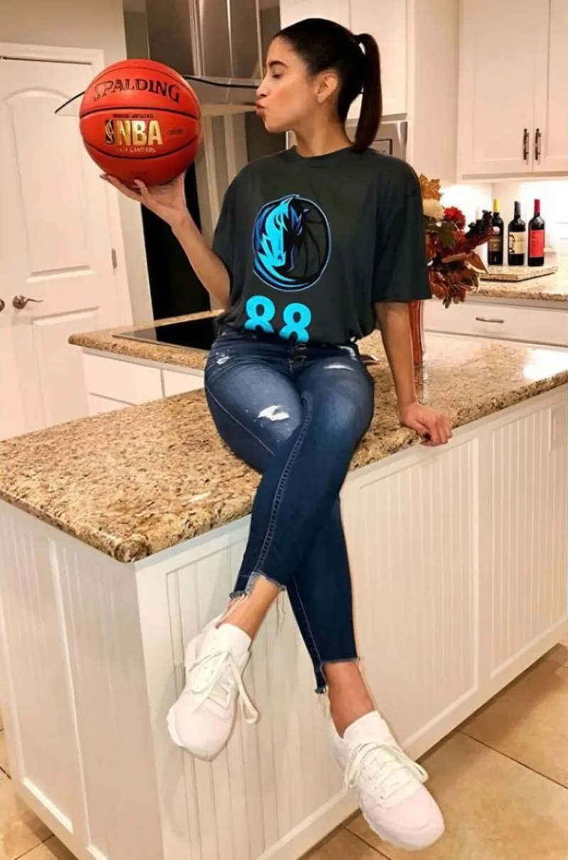 Woman poses sitting on kitchen counter holding a basketball