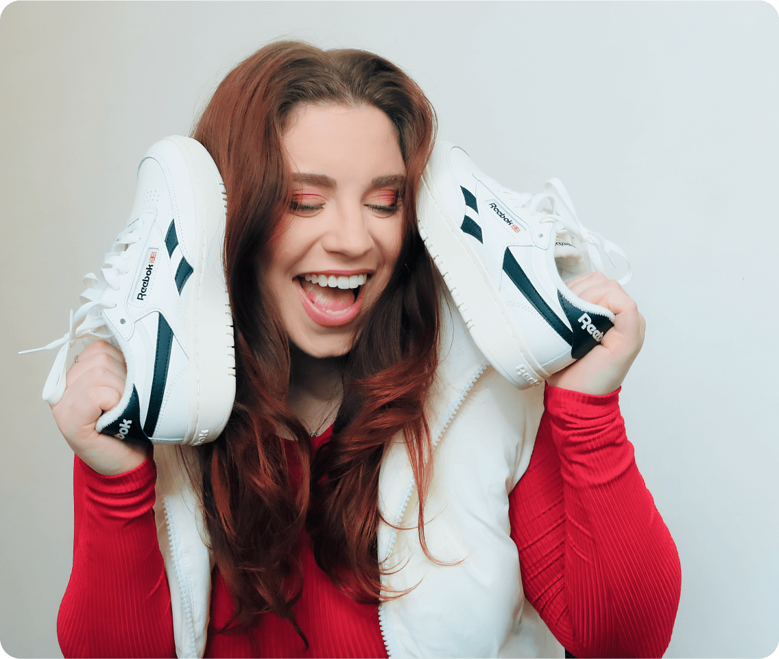 Creator laughs while holding shoes with text overlay reading 8.3K earned media value