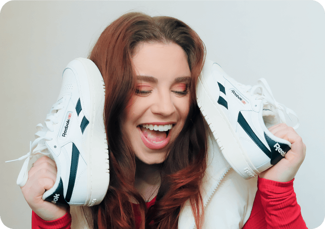 Creator laughs while holding shoes with text overlay reading 8.3K earned media value