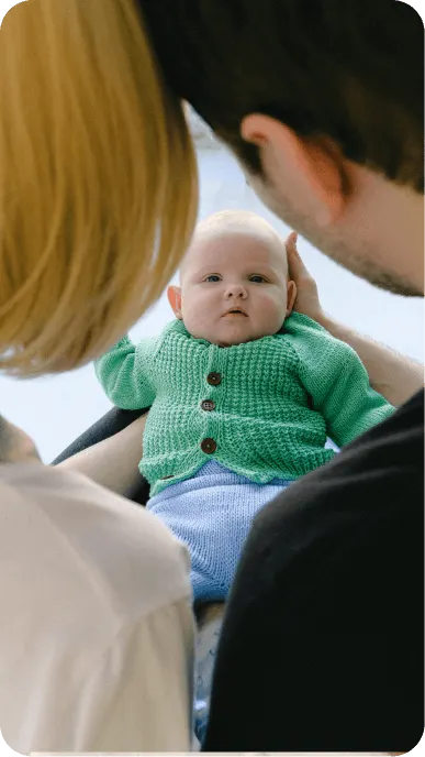 Parents hold baby wearing knitted green cardigan