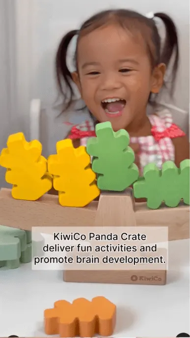 Girl with pigtails is delighted with a toy she received in KiwiCo Panda Crate