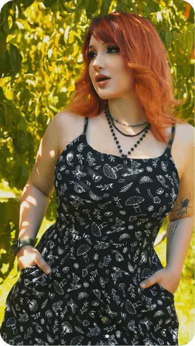 Creator with red hair poses in black patterned hot topic dress