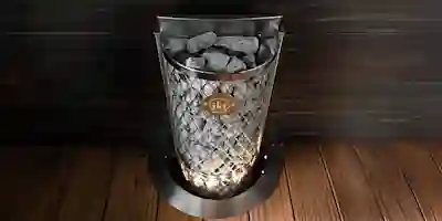 IKI electric sauna heater with diamond-patterned metal mesh and stones, on a wooden floor in front of a dark wood-paneled wall.