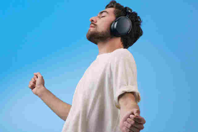 Mies fiilistelee musiikka sangalliset kuulokkeet korvillaan ja tanssahtelee samalla. Tutustu Audio ja hifi -tuotteisiin!