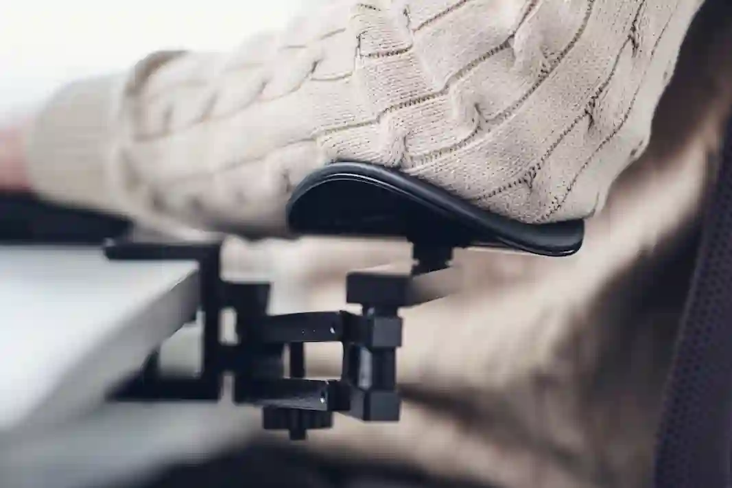 An arm resting on an ergonomic desk-mounted armrest at a workstation.